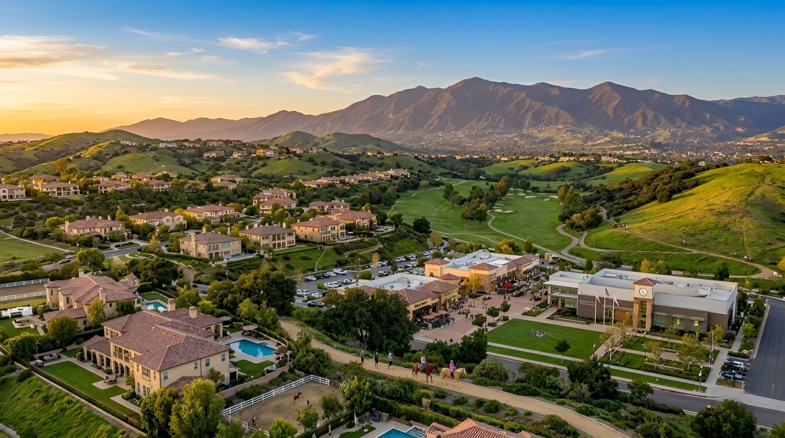 Aerial view of green valley with homes and mountains.