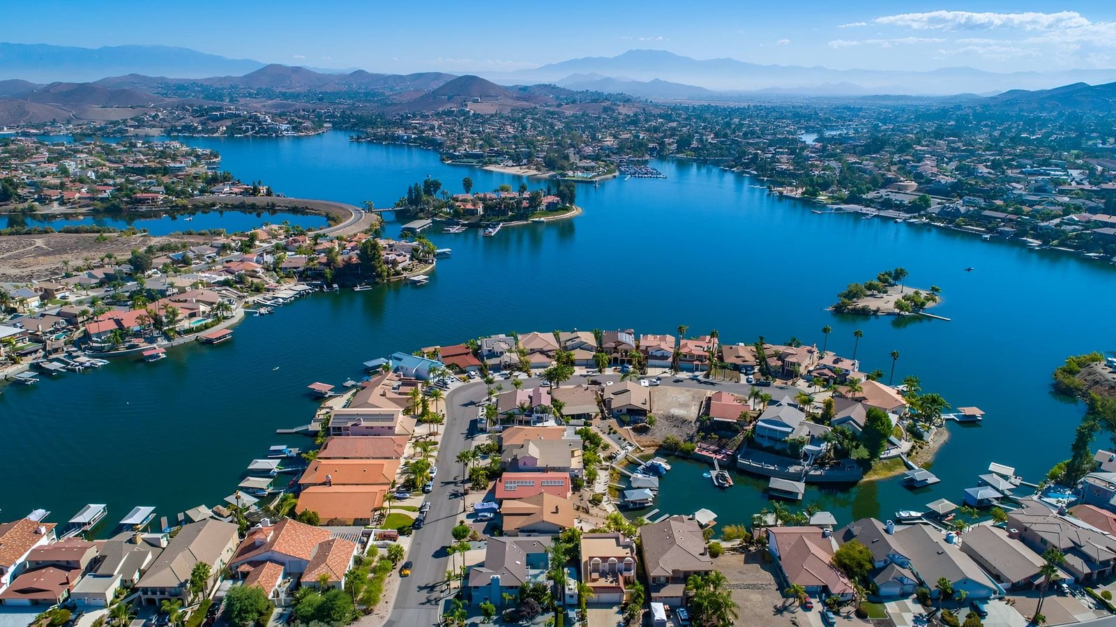 Blue lake community with homes and mountains.