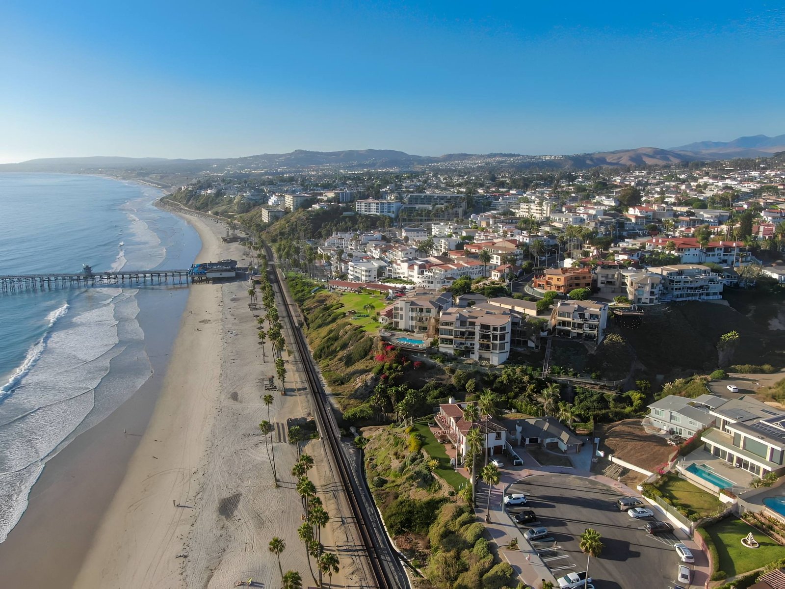 Coastal city with ocean, hills, and homes.